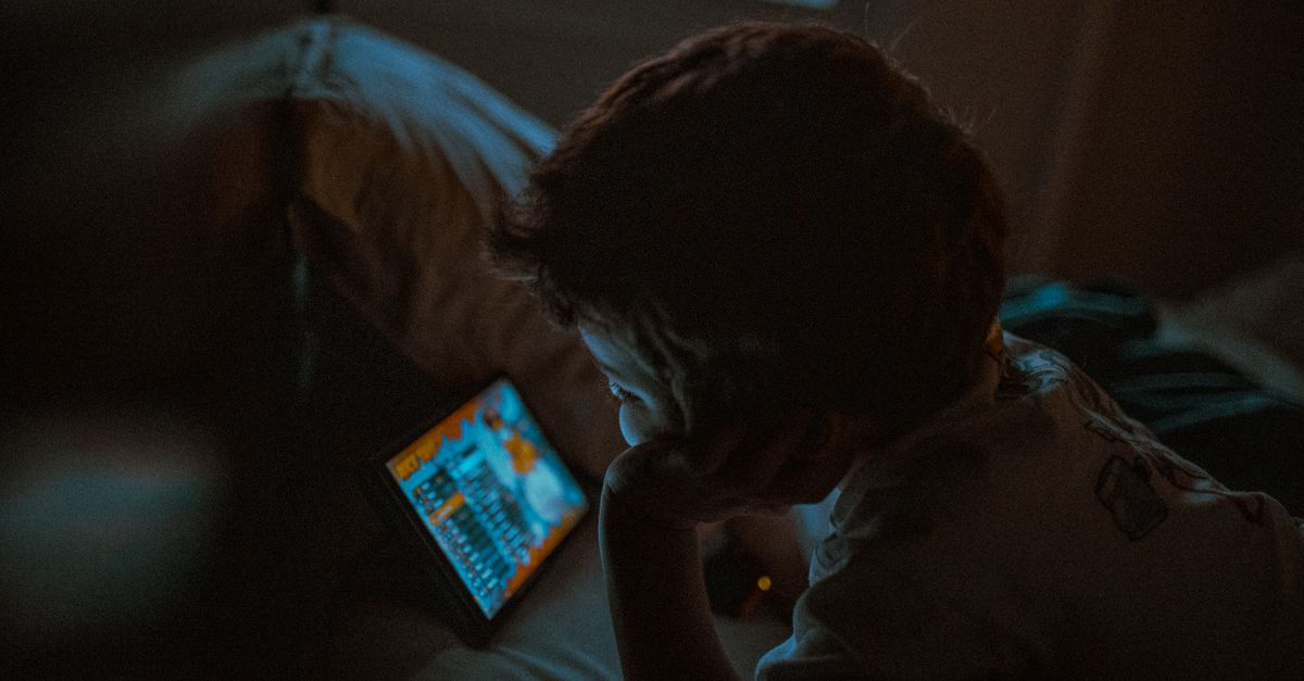 Enfant regardant une tablette, avec un sablier symbolisant le temps d'écran limité
