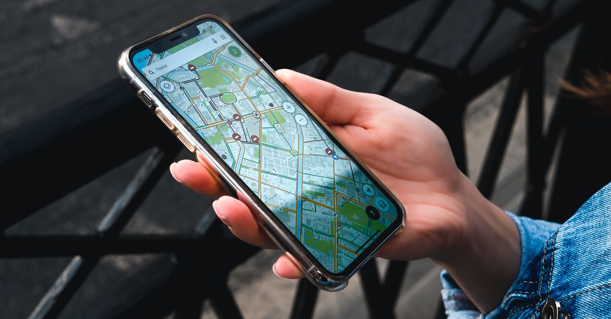 Traceur GPS miniature posé à côté d'un smartphone affichant une carte